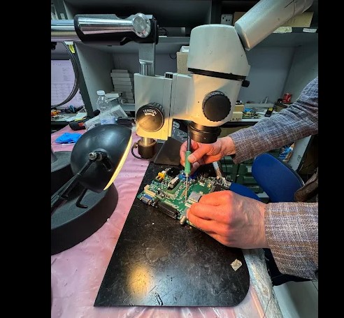 Tecnico TecnoVideo al microscopio su scheda elettronica TV